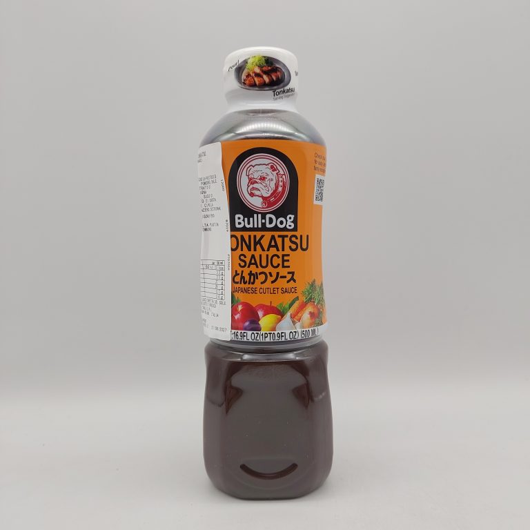 Bottiglia di salsa Tonkatsu Bull-Dog da 500ml sdraiata su uno sfondo bianco, con etichetta arancione e nero che mostra l’iconico logo del bulldog e immagini di frutta e verdura, mentre il tappo bianco riporta un’immagine di tonkatsu. La bottiglia trasparente lascia intravedere il colore scuro e denso della salsa all’interno.