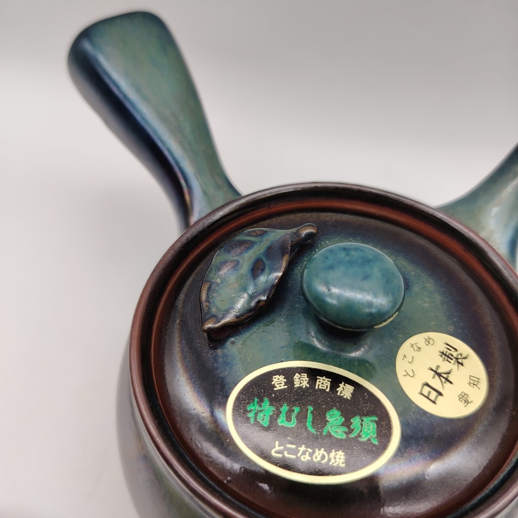 Kyusu in ceramica verde con fogliolina decorativa e coperchio, etichetta "Made in Japan" e "tokoname-yaki". Capacità 380ml.
