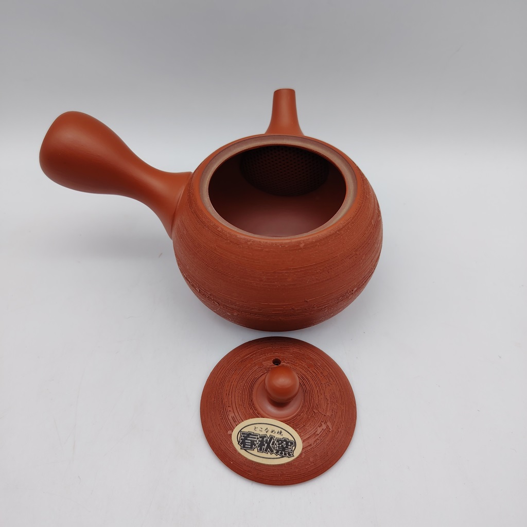 Kyusu rossa "matsukawa" 180ml con corpo e maniglia in ceramica e coperchio in legno su sfondo bianco