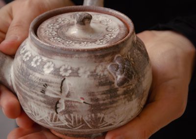 An artisan holding an ancient Japanese sake vessel with a stylized bird.