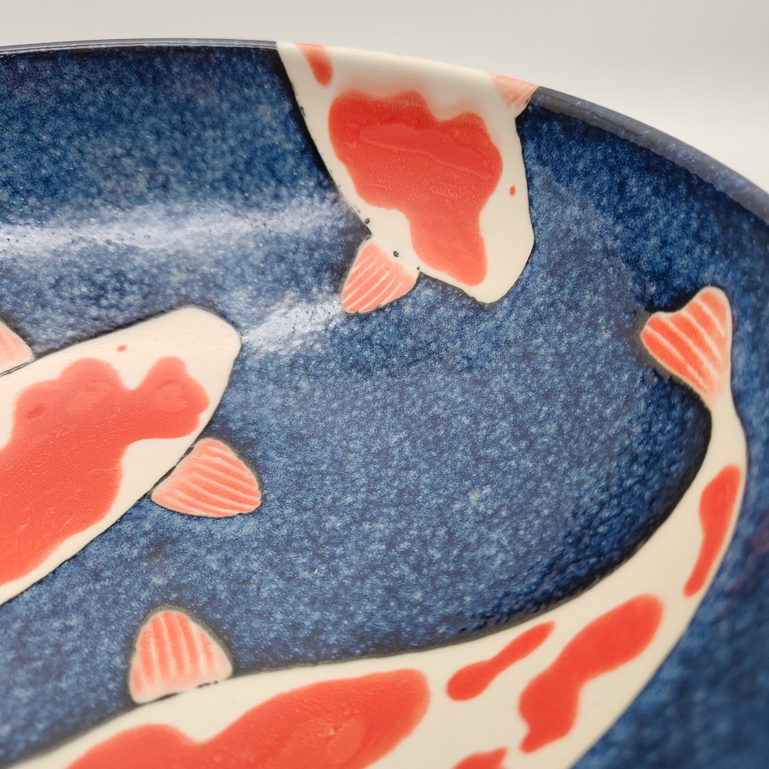 Ciotola da ramen in ceramica blu con decorazione di carpe koi arancioni e bianche. Parte di una ciotola da ramen con carpe koi.