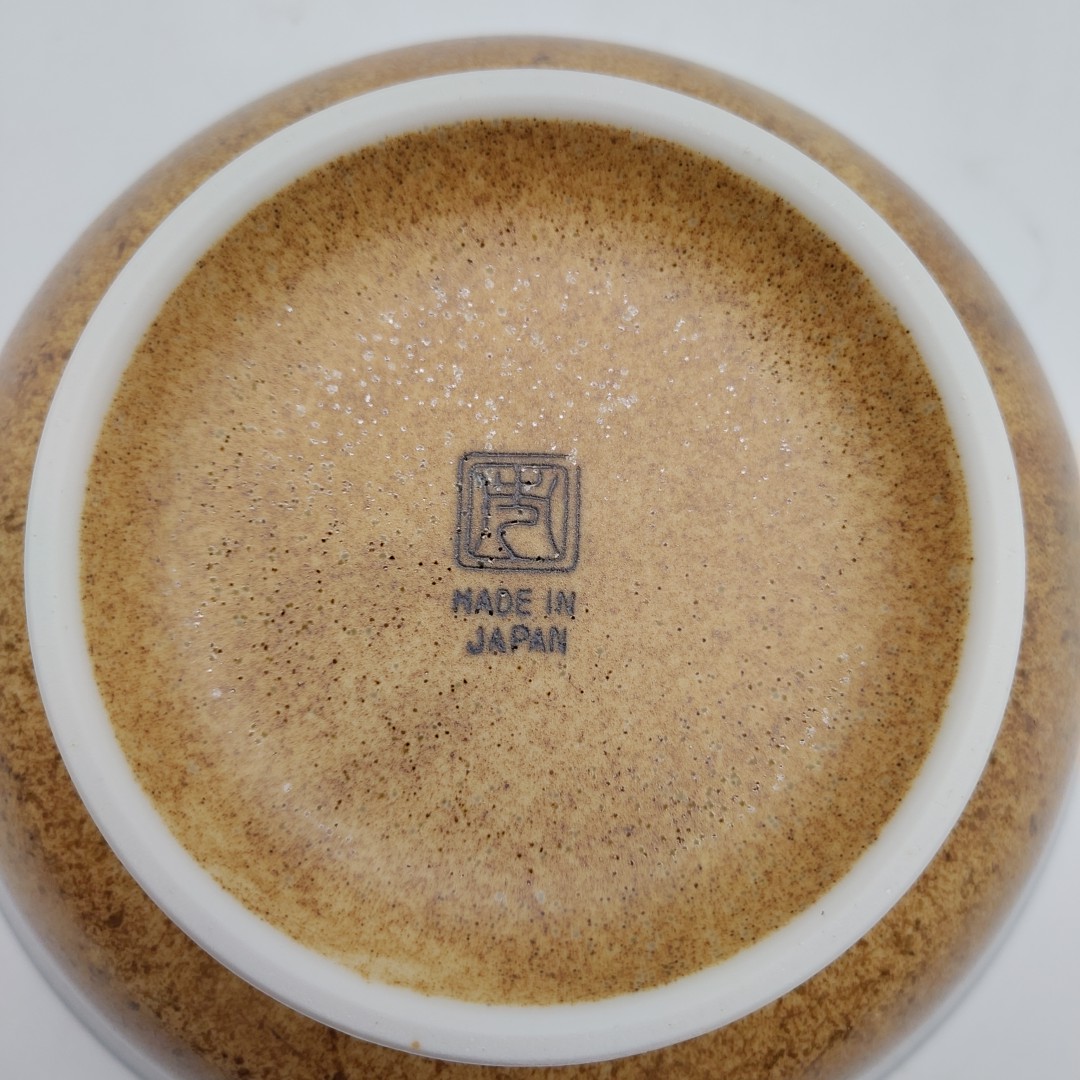 Sfondo marrone con bordo bianco, logo "MADE IN JAPAN" nero centrale